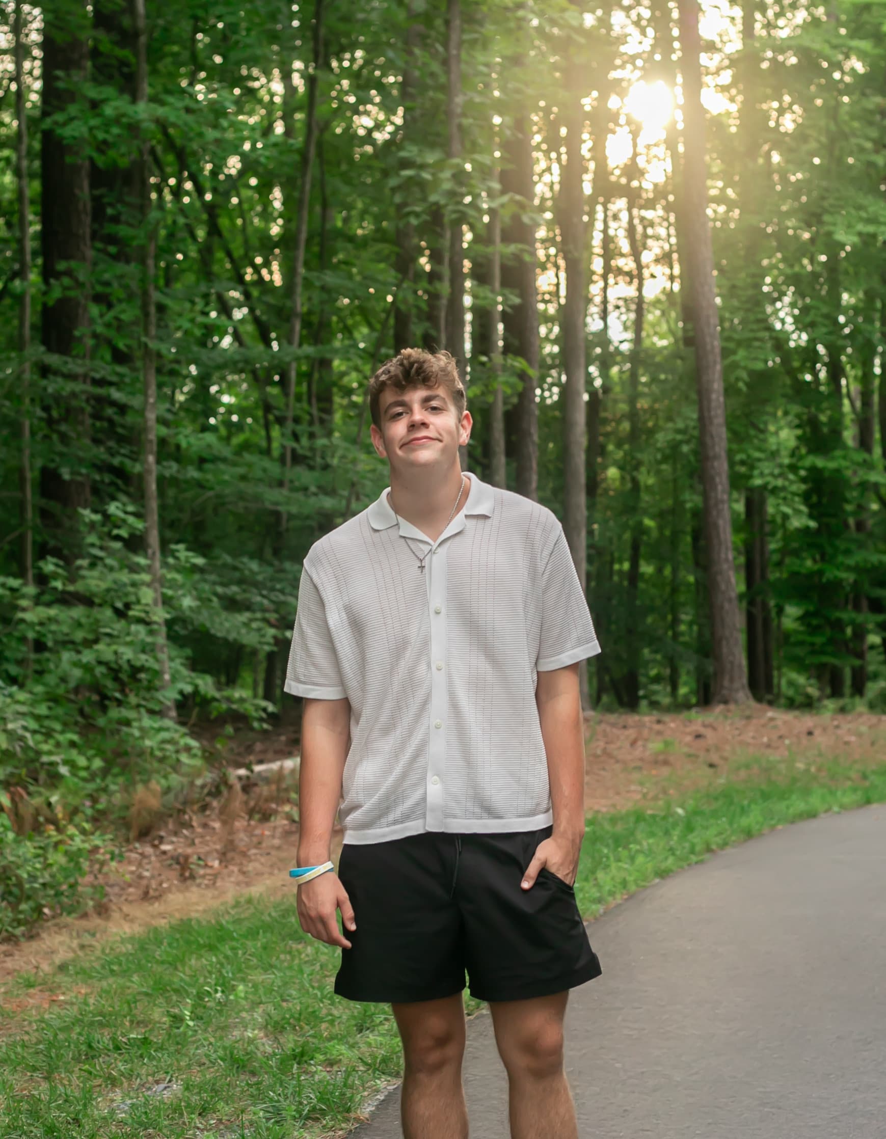 High school senior portrait on a wooded path at golden hour